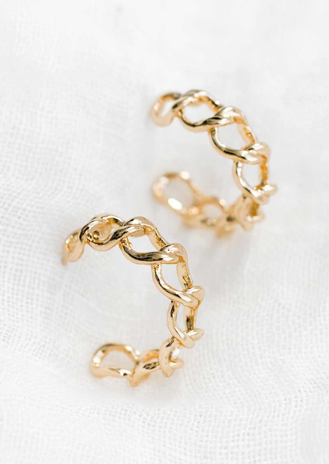 A pair of chainlink hoop earrings in gold.